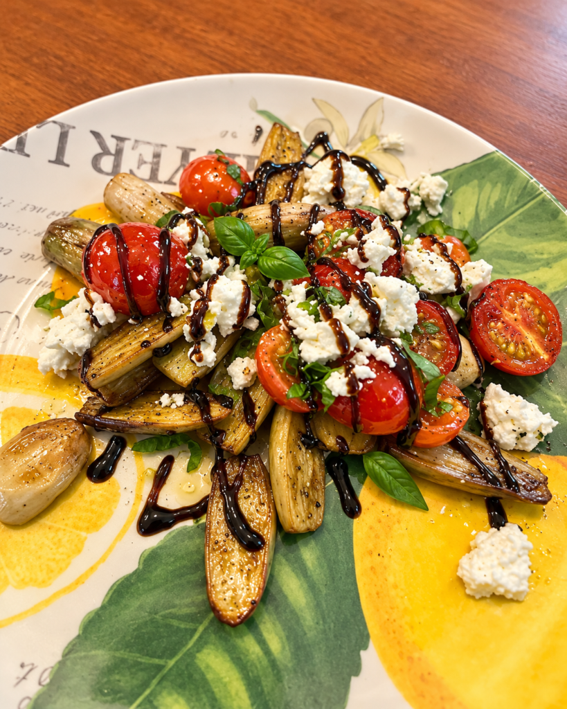 Roasted mini eggplant with garden tomatoes, fresh basil, feta and balsamic drizzle on a lemon-patterned plate.