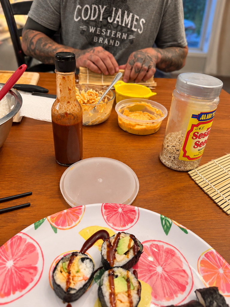 Casual family sushi-making night with homemade sushi rolls, sauces and bamboo rolling mats on a wooden table.