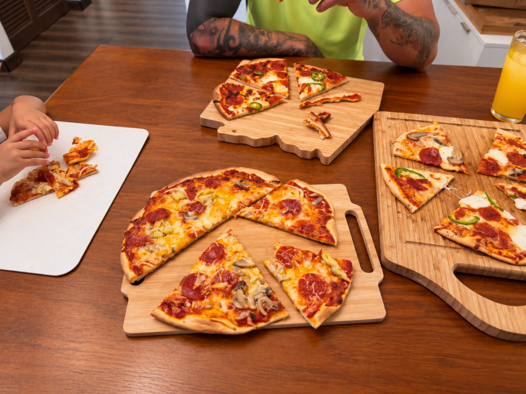 Casual family pizza night with several homemade pizzas on wooden cutting boards and family members gathered at the table.